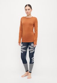 Rust-colored long-sleeve top and navy leggings with geometric patterns in gray and textured accents. Fabric appears soft and flexible.
