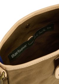 Εσωτερικό μπεζ υφασμάτινης τσάντας με σκούρο καφέ φόδρα και μαύρη ετικέτα με την επιγραφή "Η Barbour αγαπάει και τον Paul Smith" ραμμένη στο εσωτερικό.