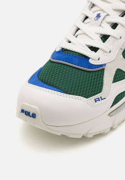 Balts sporta apavi ar zaļiem sieta elementiem, ziliem un pelēkiem akcentiem. Iespējas auklas un "Polo RL" logo sānos un aizmugurē. Gumijas zole atbalstam.