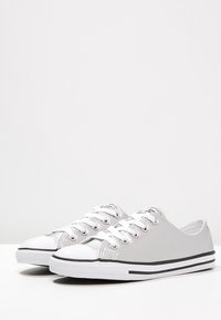 Graue Leinenschuhe mit weißem Zehenbereich, schwarzen Akzenten und runden Schnürsenkeln. Niedrig geschnittenes Design mit glatter Textur und flacher Sohle.