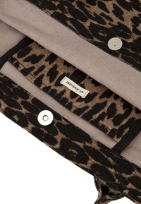 Tkanina w cętki lamparta w odcieniach brązu i czerni, charakteryzująca się gładką teksturą oraz srebrnymi zatrzaskami. Wnętrze wykończone jest jasnym beżem.