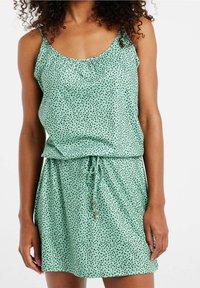 Robe vert menthe à motif à pois, taille cintrée et bretelles spaghetti. Tissu doux et léger avec une coupe décontractée et un col froncé.