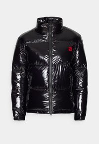 Błyszcząca czarna kurtka puchowa z kołnierzem typu stójka, przednim zamkiem, zamykanymi bocznymi kieszeniami oraz małym czerwonym logo "HUGO" na piersi.