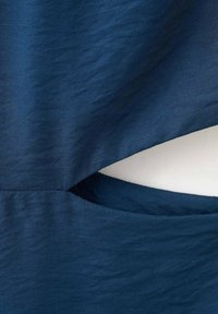 Námornícka modrá látka s hladkou textúrou, obsahujúca vyrezávaný detail a vrecko. Dizajn má čisté línie a presný tvar.