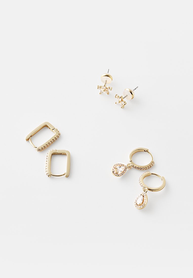 Boucles d'oreilles en or comprenant des formes carrées et en goutte d'eau, avec une paire ornée de strass. Surface en métal lisse avec une finition brillante.