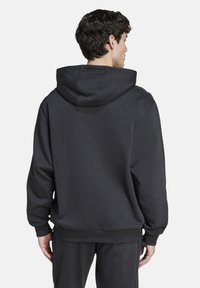 Felpa nera realizzata in tessuto misto cotone. Presenta un cappuccio con coulisse, polsini e orlo a costine. Texture liscia senza motivi visibili.