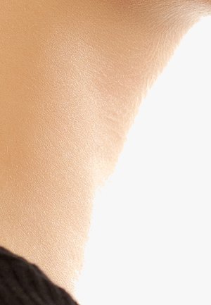 Close-up of textured beige wall with light casting a soft shadow, partially framed by a black fabric edge in the bottom left corner.