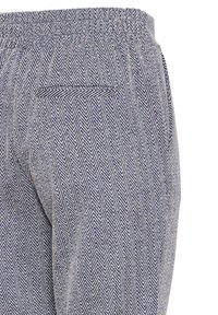 Nohavice s herringbone vzorom v odtieňoch modrej a krémovej, s elastickým pásom a zadnou vreckom pre praktickosť.