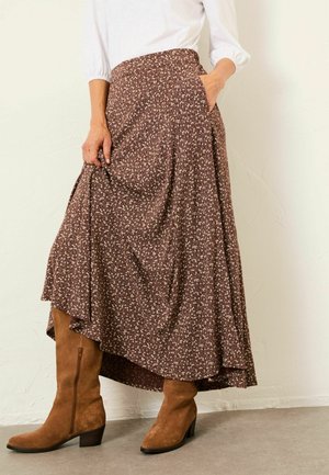 Brown floral-print maxi skirt with a high-low design, made from a soft, textured fabric, paired with knee-high brown suede boots.