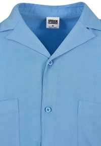 Chemise bleu clair à manches courtes avec col camp, deux poches avant et boutons, taille M, marque Urban Classics.