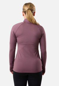 Top atletico a maniche lunghe in malva, realizzato in un tessuto liscio e elastico. Presenta un colletto alto e un design aderente, con maniche raglan per facilitare il movimento.
