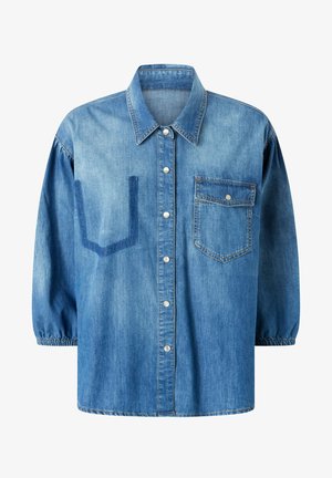 Traper košulja svijetloplave boje s dugmadi sprijeda, šiljastim kragnom i džepom na prsima. Ima naglašene rukave i U-oblikovani detalj sprijeda.