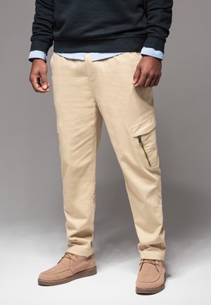 Beige cargobroeken met een ritszak, rechte pasvorm, gemaakt van een katoenmix. Gepaard met bruine suède schoenen en een donker trui.