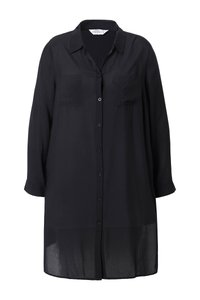 Longue robe-chemise noire boutonnée avec col, manches longues, deux poches poitrine et tissu légèrement transparent à l'ourlet.