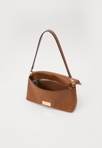 Borsa a mano in pelle marrone con una forma curvata, una tracolla corta e un accento in metallo dorato sul davanti. L'interno è rivestito di una tonalità più scura.