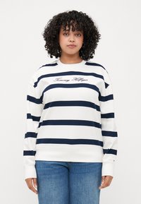 Marineblå og hvit stripete genser med ribbestrikkede mansjetter og hem; har brodert "Tommy Hilfiger"-logo på brystet. Myk bomullsblanding.