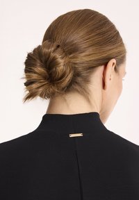 Czarny top z wysokim kołnierzem o eleganckim fasonie, z akcentem ze złotego metalu z tyłu i teksturalnym detalem w postaci koków z włosów.