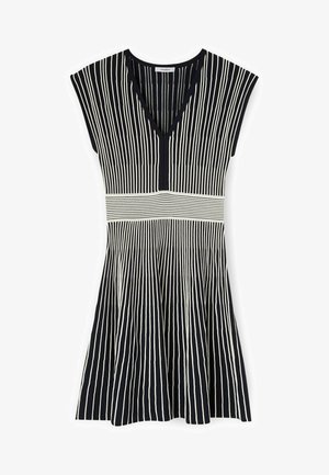 Zwart-witte mouwloze jurk met verticale strepen, V-hals en horizontale gestreepte tailleband detail.