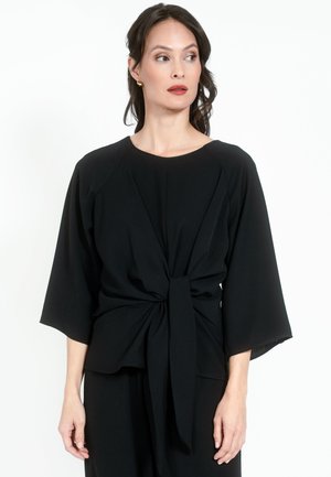 Must mustriga ümarate neelustega, laiad kolmeveerandi varrukad ja seotud eesmine detail. Valmistatud kergest kangast, millel on sile tekstuur.