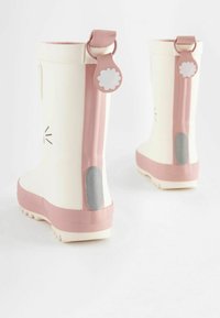 Bottes en caoutchouc blanches avec des accents roses, une languette en forme de fleur et une pièce grise texturée au talon. Design à tige courte, semelle robuste.