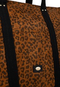 Borsa tote in canvas marrone con stampa leopardata, dotata di manici neri e dettagli del logo in tono oro. Caratterizzata da una tasca frontale e una superficie testurizzata.