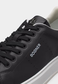 Μαύρο δερμάτινο αθλητικό παπούτσι με μαύρα κορδόνια, λευκή σόλα και λογότυπο "BOGNER" στο πλάι, κλειστή γωνιακή όψη.