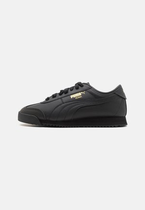 Baskets Puma Roma en cuir noir avec logo doré, lacets noirs et semelle texturée sur fond neutre, vue de côté.