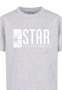 Šedé bavlněné tričko s předním grafickým logem "S.T.A.R. LABORATORIES" s ostrými designovými prvky v bílé barvě. Krátké rukávy, klasický dobře padnoucí výstřih.