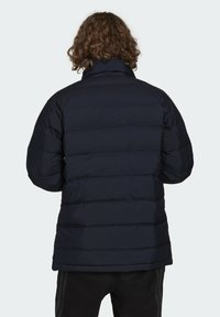 Giacca puffer navy con trapuntatura orizzontale, colletto alto e polsini elasticizzati. Il materiale appare liscio e isolato, progettato per il calore.