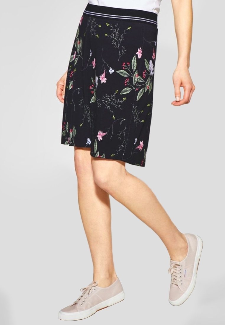 Mustat, kukkakuosiset hameet, joissa on pehmeä rakenne, joustava vyötärö ja polvipituisuus, yhdistettynä vaaleanpunaisiin tennareihin.