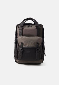 Sac à dos en tissu gris foncé avec des accents noirs. Comprend un compartiment principal, un rabat avant avec des fermetures à boucle et deux poignées supérieures.
