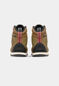 Bottes de randonnée marron avec semelles noires et accents gris. Présentent un design mi-haut, un cuir texturé et une bande rouge au niveau du talon.