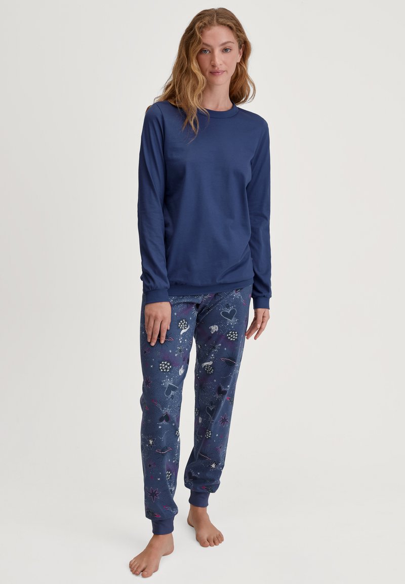 Donkerblauwe langemouwen shirt gecombineerd met gestreepte pyjamabroek met sterren, harten en bloemenpatronen in heldere kleuren, gemaakt van zachte katoen.