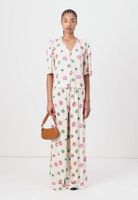 Floral-patterned two-piece set in cream includes short-sleeve button-up top and wide-leg pants. Tan handbag as an accessory.