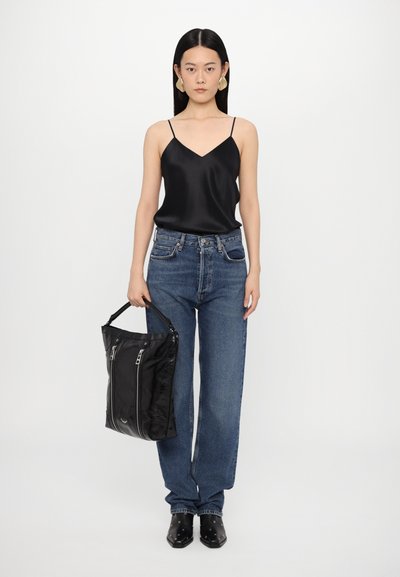 Camisole din satin negru, blugi deschiși la culoare, cu talie înaltă, geantă tote neagră cu fermoar și pantofi negri cu vârf ascuțit, decorați cu studuri argintii.