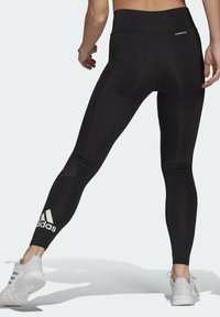 Czarne legginsy z wysokim stanem, o dopasowanym kroju, z bocznymi panelami z siatki i logo Adidas na dolnej części nogawki. Miękka, elastyczna tkanina.