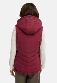 Bordowa ocieplana kamizelka z kapturem, wykonana z pikowanego materiału w kształcie litery V, z bocznymi zatrzaskami i naszywką z logo przy kołnierzu. Miękka tkanina o matowym wykończeniu.