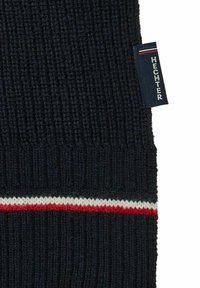 Écharpe en laine de couleur bleu marine foncé avec une texture côtelée. Présente une bande horizontale rouge et blanche près du bas et une étiquette sur le côté portant la mention "HECHTER".