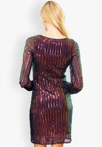Robe courte à manches longues avec un motif de sequins multicolores à rayures verticales, créant une texture scintillante et une silhouette ajustée.