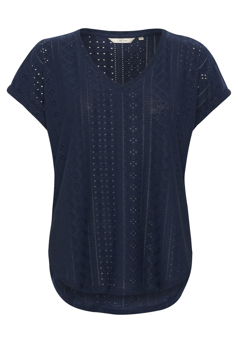 Jūras zilas krāsas tops ar V veida kaklu, īsām piedurknēm un teksturētu rakstu, kas ietver izgrieztus elementus un ģeometriskas formas. Noapaļots apakšmalas dizains.