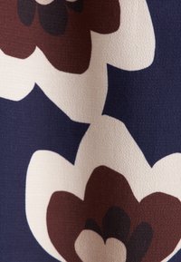 Stof met bloemenpatroon met grote roomwitte en kastanjebruine bloemen op een donkerblauwe achtergrond; zachte textuur en gladde afwerking.