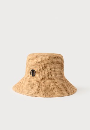 Bob tissé beige à large bord avec un petit logo noir circulaire sur le côté, sur un fond uni clair.