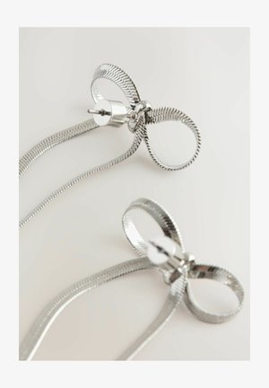 Silberne Ohrringe mit einem gedrehten, bandartigen Design, das eine geschwungene Schleife und eine zylindrische Rückseite aufweist. Glatte, metallische Textur.