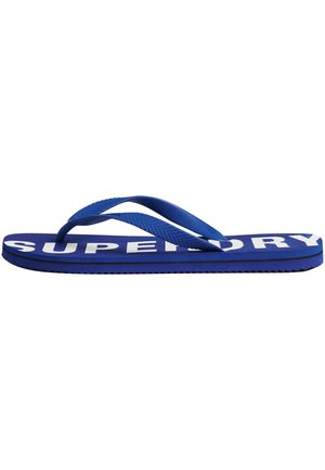Blauer Gummilatschen mit einem strukturierten Riemen und großem weißen "SUPERDRY"-Logo auf der Fußbett. Besitzt eine gerippte Sohle für besseren Grip.