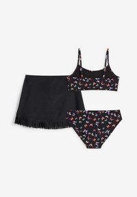 Set bikini nero con motivo floreale e farfalle, top a triangolo, slip coordinato e una gonna nera con dettagli di frange.