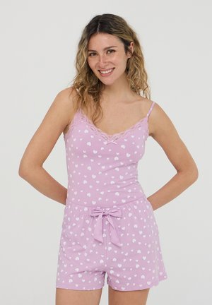Set di pigiama rosa chiaro con motivi di cuori bianchi. Il canottiere presenta un bordo in pizzo, mentre i pantaloni corti hanno una vita elasticizzata e un dettaglio a fiocco.