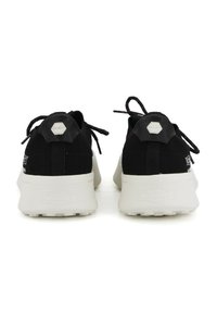 Scarpe da ginnastica nere con upper in maglia testurizzata, suole bianche e accenti esagonali sul tallone. Presentano lacci e un colletto imbottito.