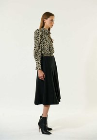 Melna svārku ar izplūdušu apakšdaļu, saskaņota ar krēmkrāsas blūzi ar tumšu ziedu rakstu. Modelis valkā melnas potīšu zābakus.
