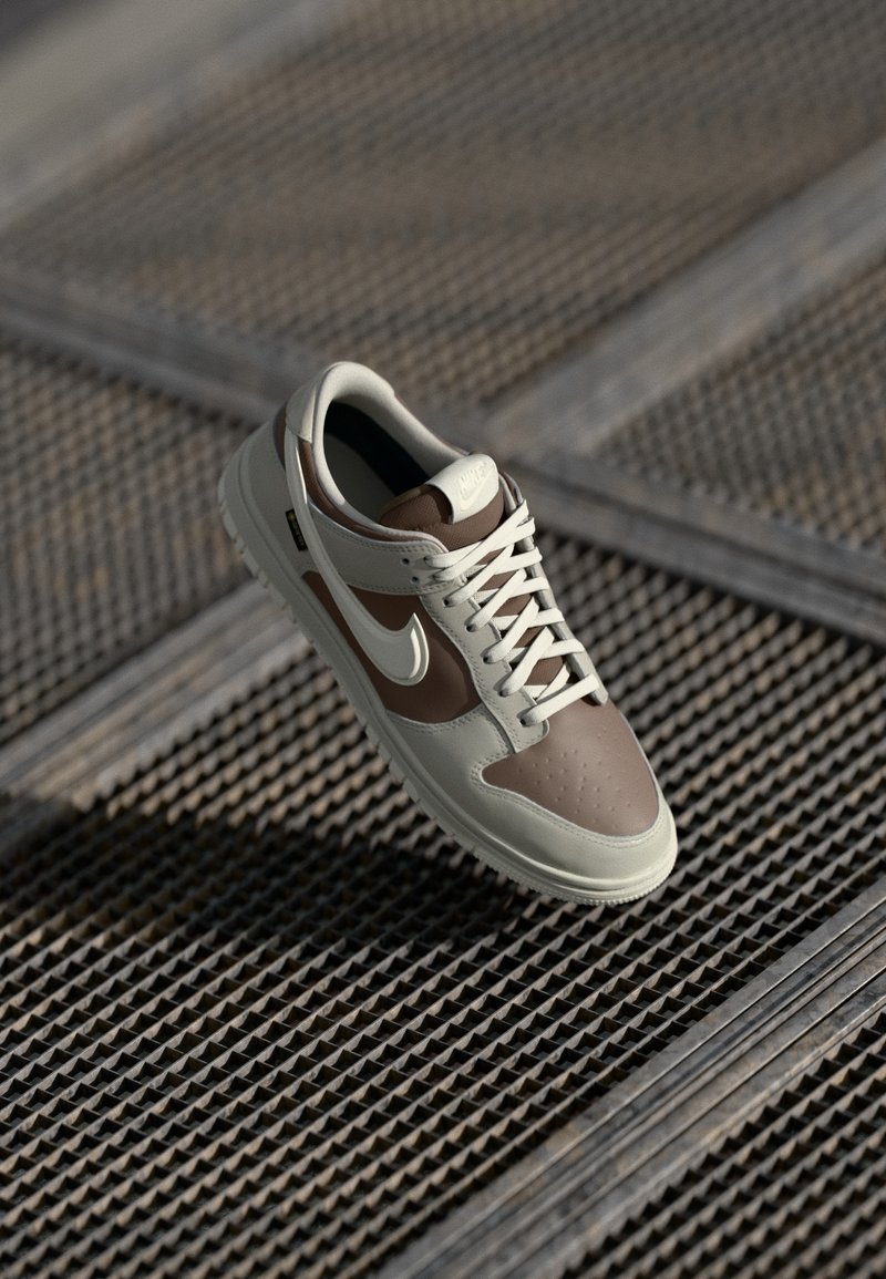 Nike tenisica s bež i smeđim gornjištem od kože, bijelim vezicama, perforiranim prstom i gumeni potplat s teksturiranim gripom.