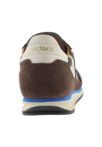 Brown suede sneaker with cream and blue accents, featuring a textured back, white logo, and a contrasting rubber sole.